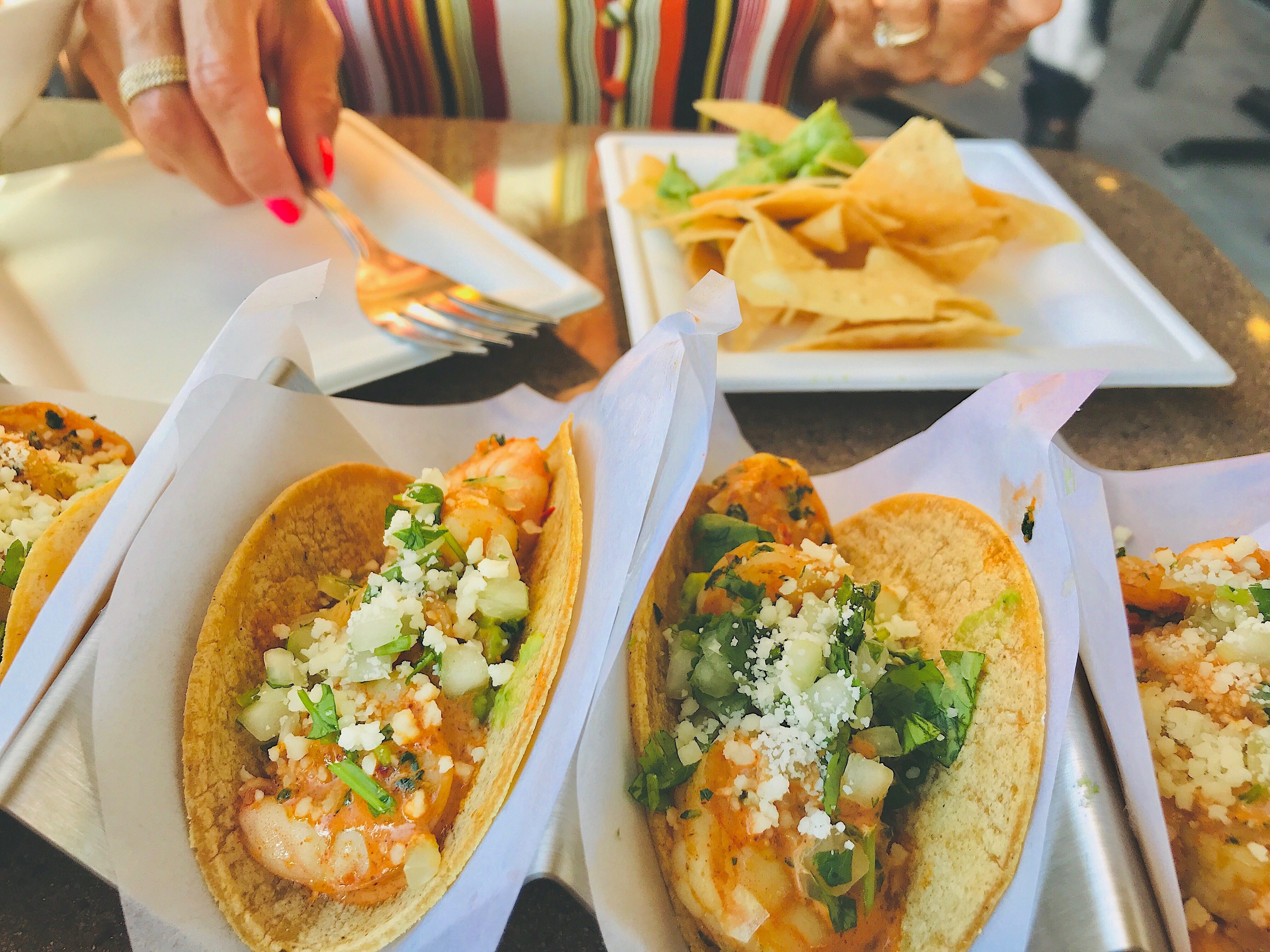 shrimp tacos topped with diced onions, cilantro, and cheese